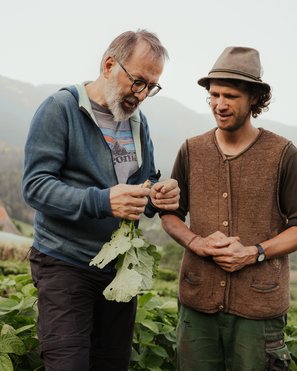 Atelier Moessmer Norbert Niederkofler Two men inspecting a vegetable plant in a farm field