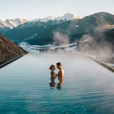 Unser Hotel mit Fitnessstudio in Südtirol Paar im Infinity-Pool mit Blick auf verschneite Berglandschaft
