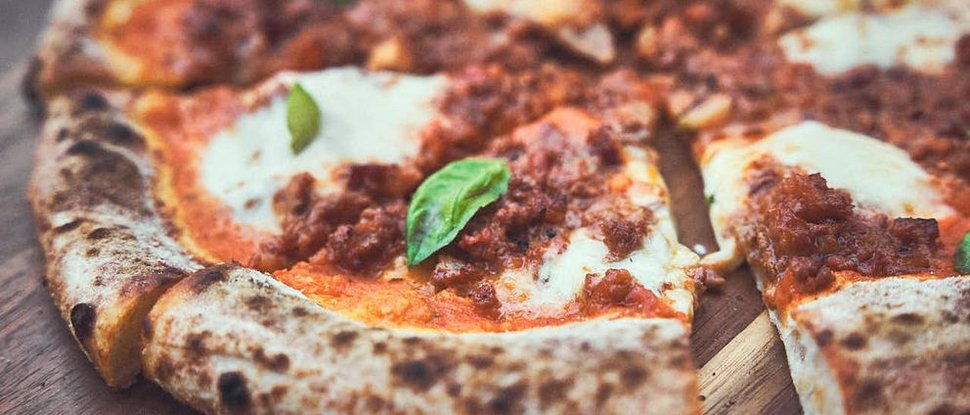 Current news and stories from Olang Pizza with tomato sauce, mozzarella, and basil on a wooden table