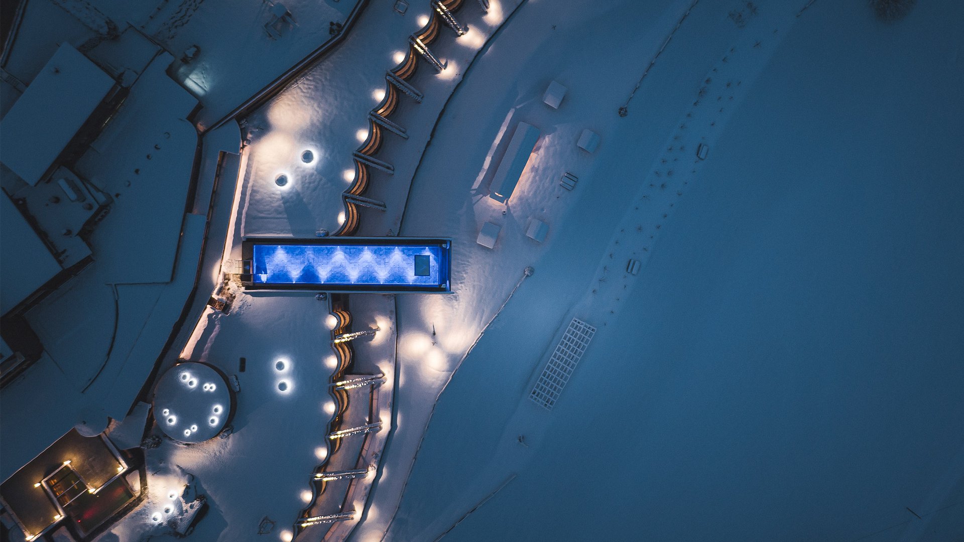 Unsere Parks, Ihre Rückzugsorte Luftaufnahme eines beleuchteten Swimmingpools und verschneiter Umgebung bei Nacht