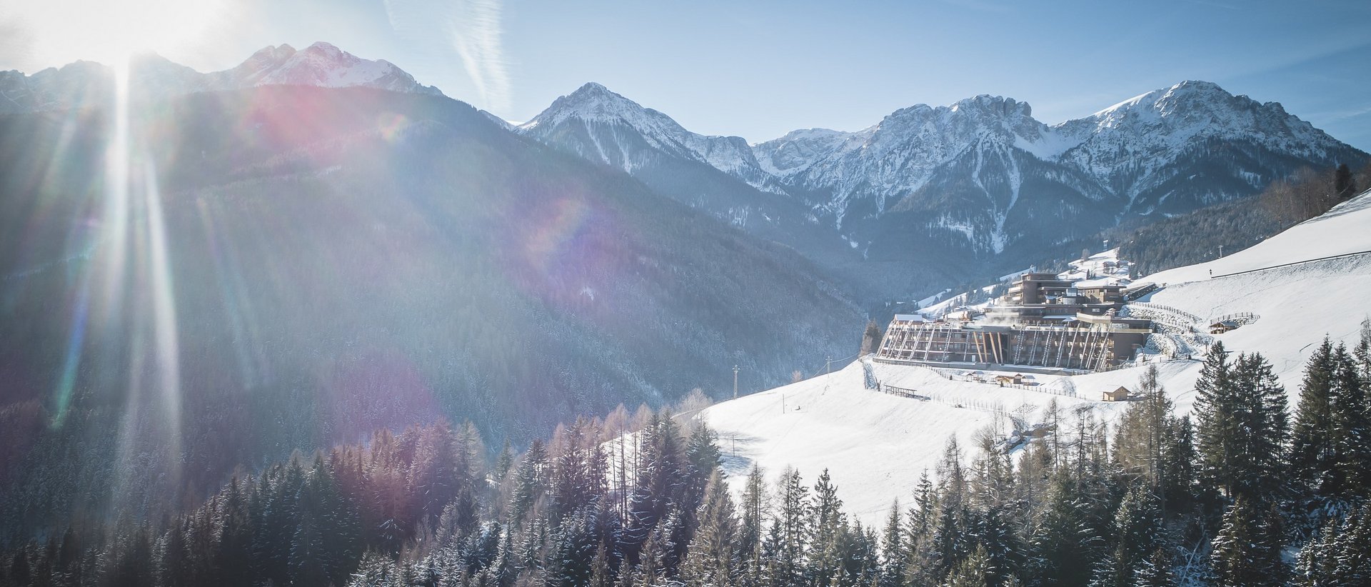 Hotel im Pustertal mit 5 Sternen Sonniger Wintertag in den verschneiten Bergen mit Wald und Gebäude