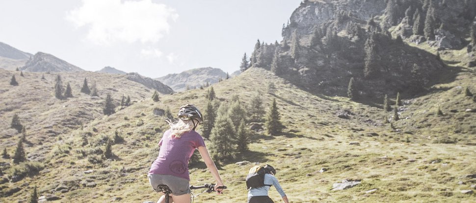 Aktuelle News und Geschichten aus Olang Zwei Mountainbiker fahren auf einem Pfad in den Bergen bei sonnigem Wetter