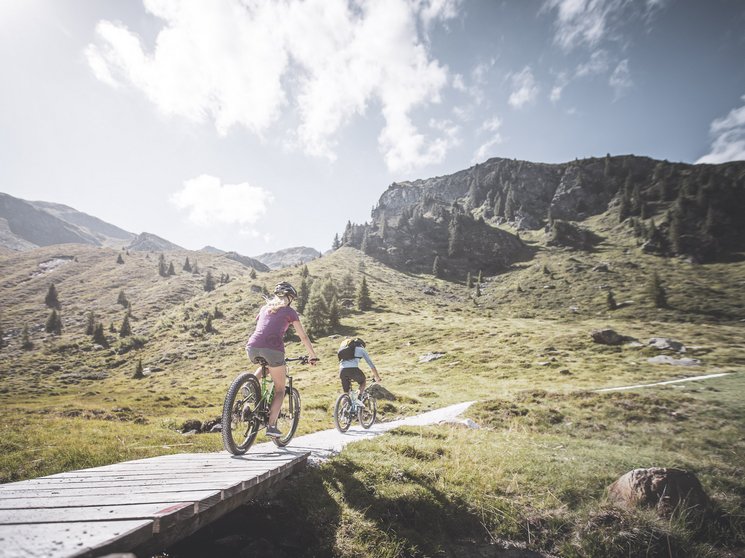 Biking at Plan de Corones/Kronplatz: unique Two mountain bikers riding on a trail in the mountains on a sunny day