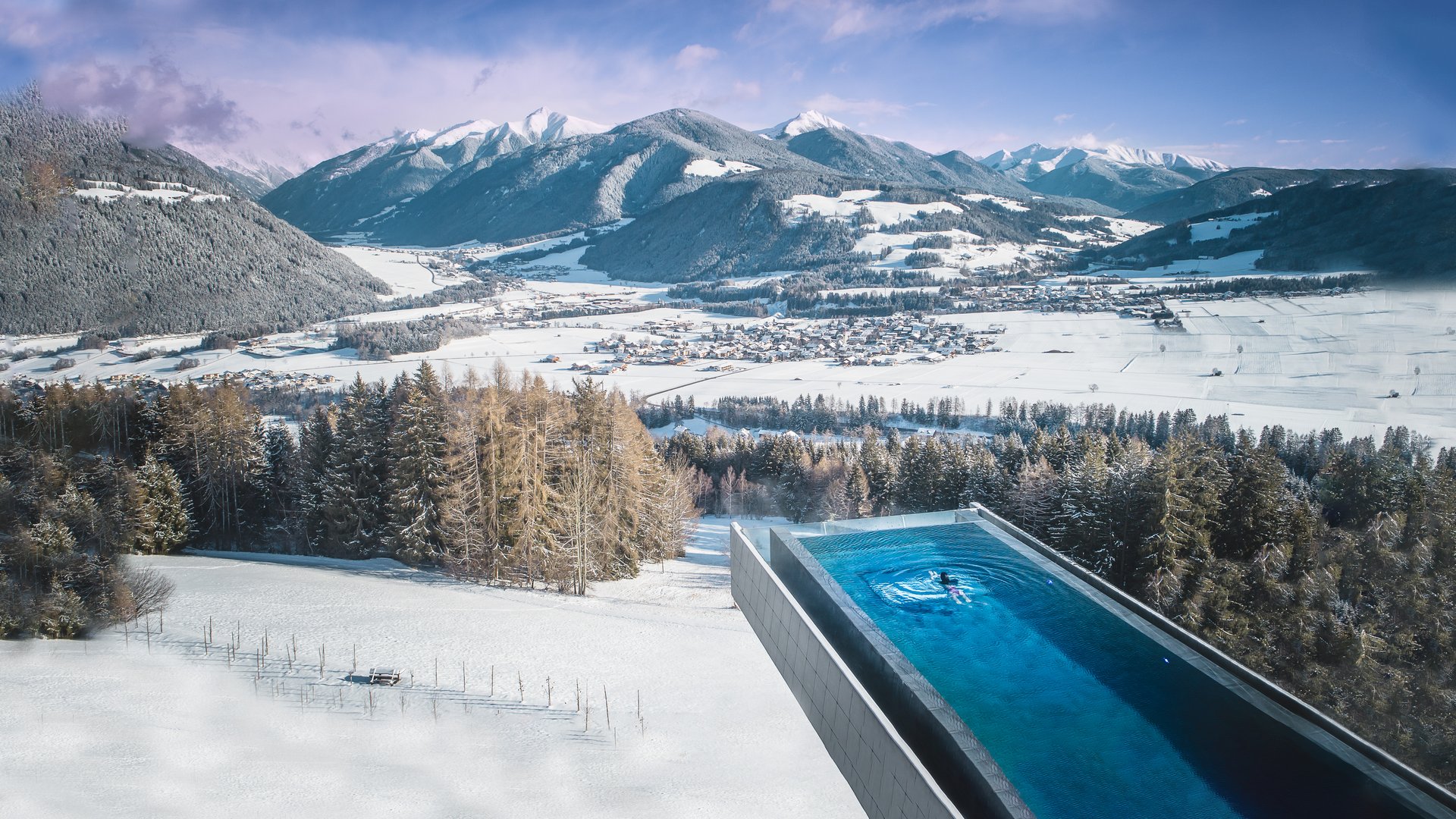 Unser Hotel in Olang zwischen Himmel und Erde Infinity-Pool mit Aussicht auf schneebedeckte Berge und Tal im Winter