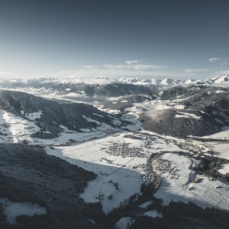 Unsere Parks, Ihre Rückzugsorte Luftaufnahme eines schneebedeckten Bergtals mit Dörfern und Bergen bei klarem Himmel