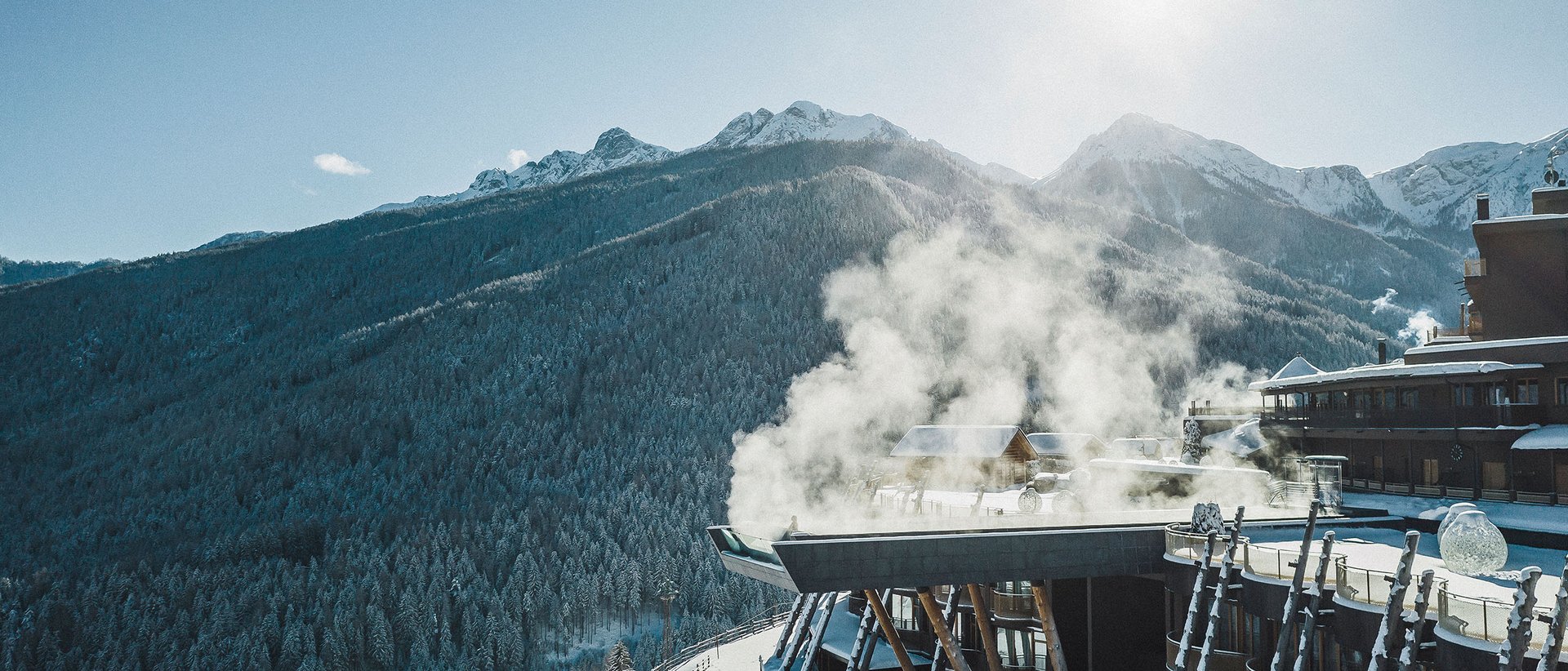 Unser Hotel in Olang zwischen Himmel und Erde Schnee bedecktes Berghotel mit rauchendem Kamin und Sonnenschein