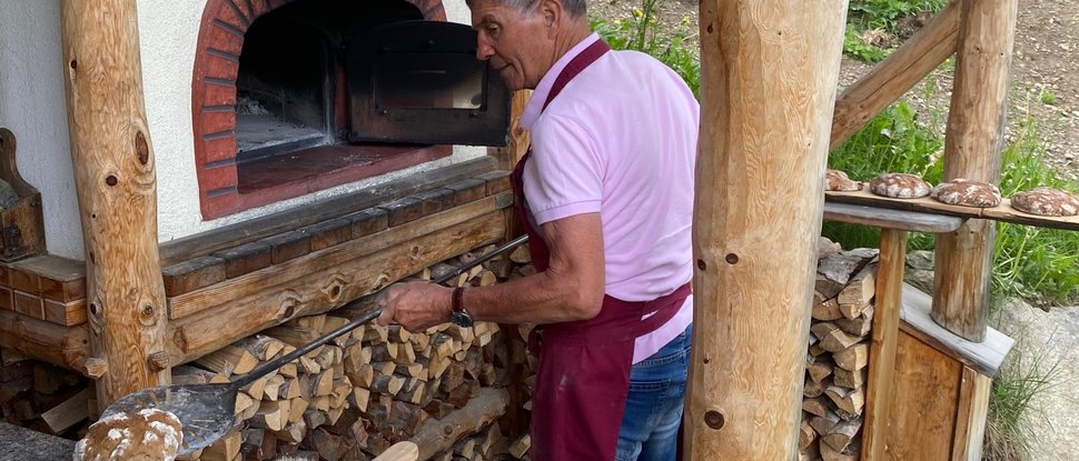 Current news and stories from Olang Man baking bread in an outdoor wood-fired oven
