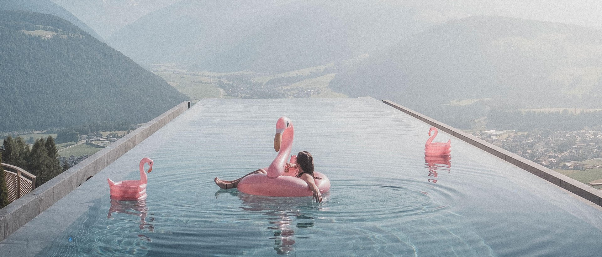 Our Sky Pool in South Tyrol, a rare beauty Person on flamingo float in infinity pool with mountain view