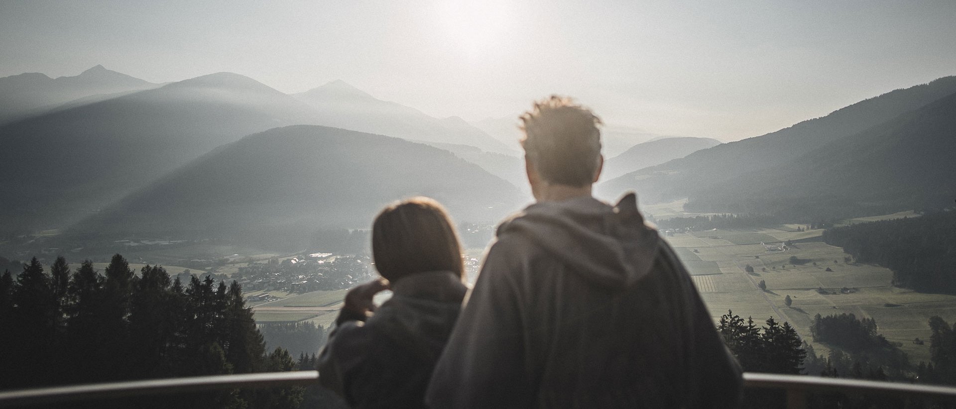 Your 5-star hotel in the Dolomites Couple looking at misty mountain landscape at sunrise