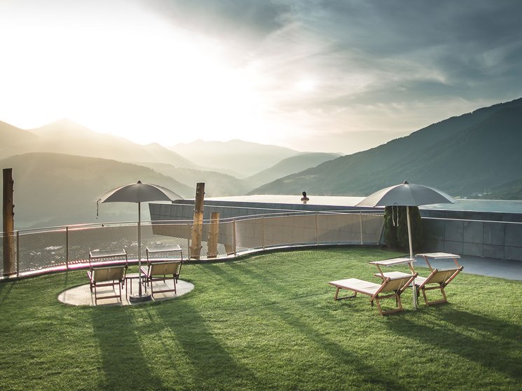 Alpenreych & Hubertus Park Sunny terrace with chairs and umbrellas overlooking mountain landscape at sunrise