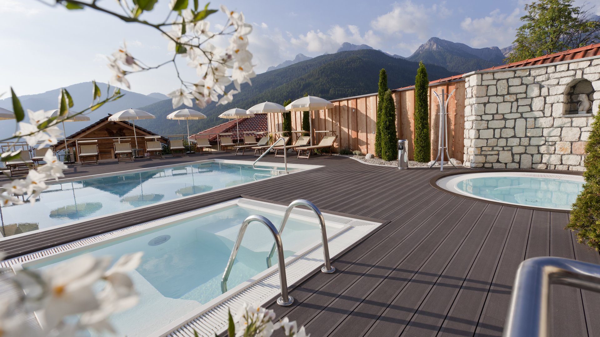 Our Sky Pool in South Tyrol, a rare beauty Outdoor pool with sun loungers and mountain view on a sunny day