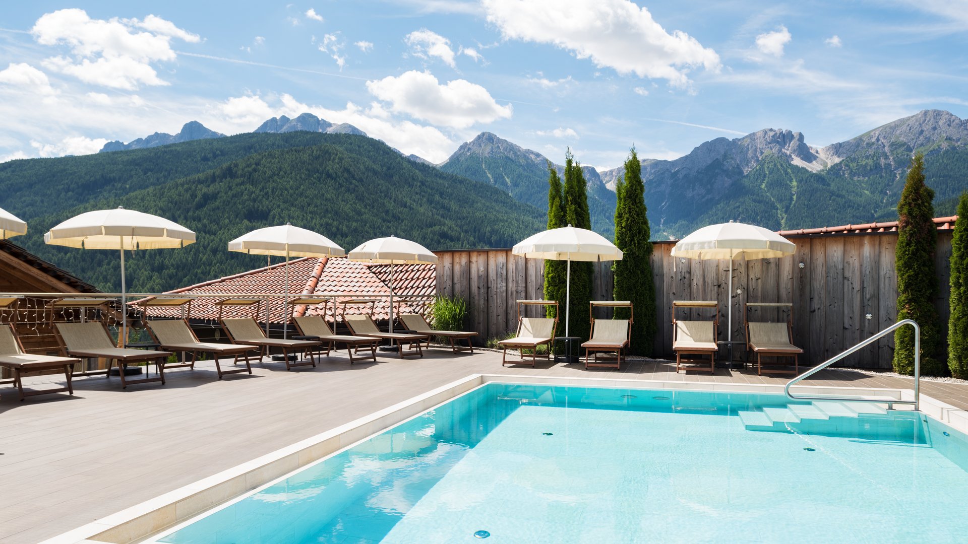 Our Sky Pool in South Tyrol, a rare beauty Pool area with loungers, umbrellas, and alpine mountains in the background