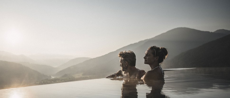 Aktuelle News und Geschichten aus Olang Paar entspannt in Infinity-Pool mit Bergblick bei Sonnenuntergang