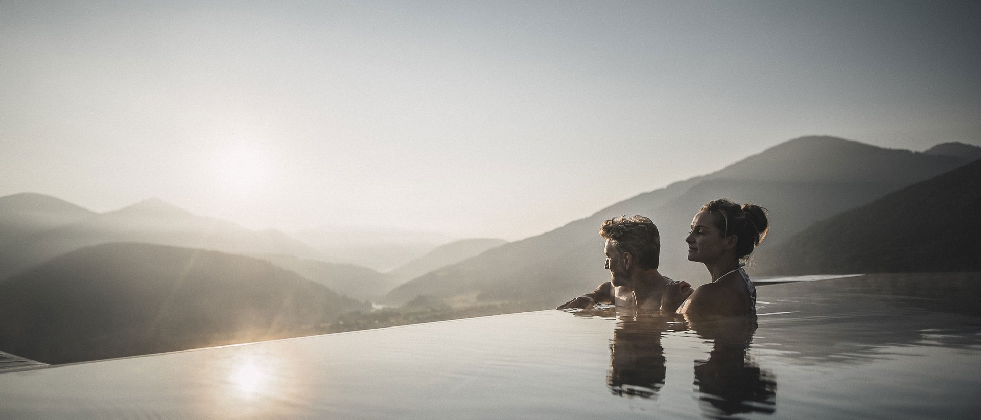 Our Sky Pool in South Tyrol, a rare beauty Couple relaxing in infinity pool overlooking mountains at sunset