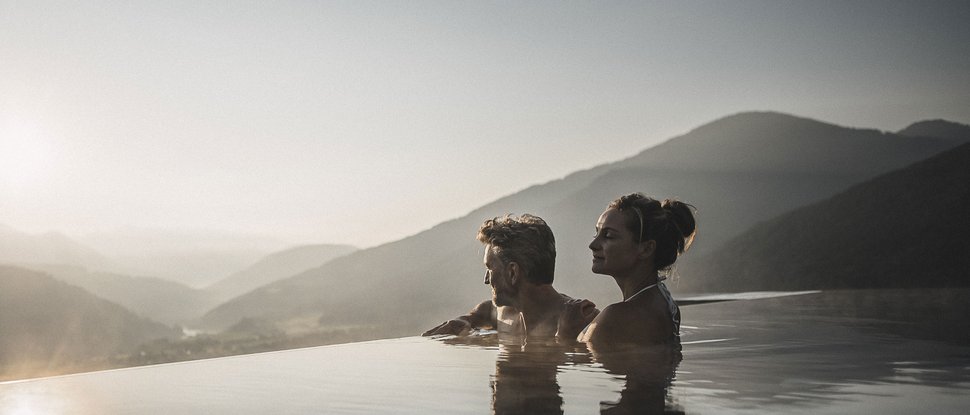 Il nostro attuale catalogo da scaricare Coppia rilassata in piscina a sfioro con vista sulle montagne al tramonto