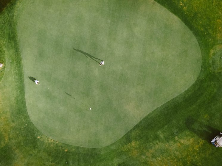 Golfclub Pustertal - Your golf course at Mt. Kronplatz Two golfers on the green with a golf cart on the golf course aerial view