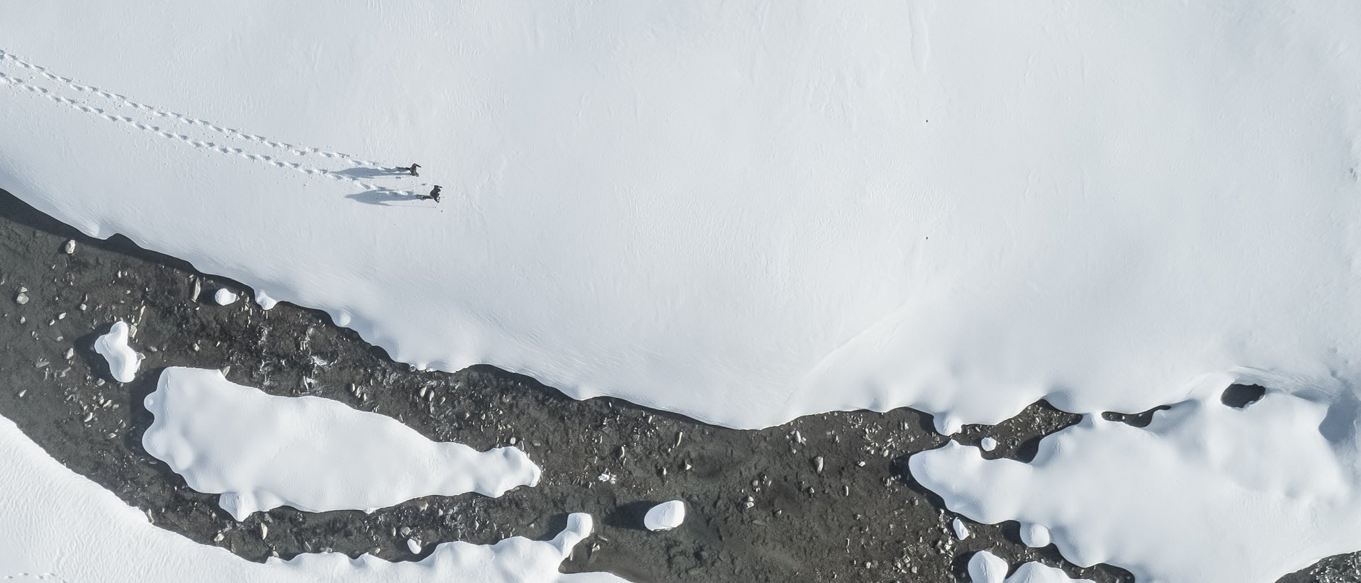 Winter hiking at Plan de Corones/Kronplatz Drone view of snowy landscape with two people and tracks in the snow