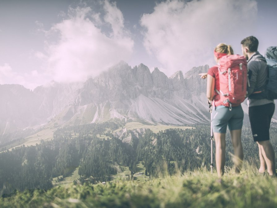 Our 5-star hotel in Italy between heaven and earth Two hikers looking at forested mountains and clouds