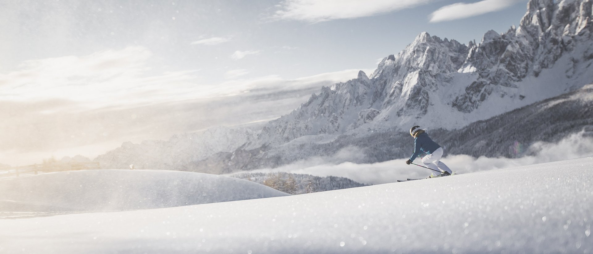 Hotel im Pustertal mit 5 Sternen Skifahrer fährt auf verschneiter Piste vor schroffen Berggipfeln bei Sonnenlicht