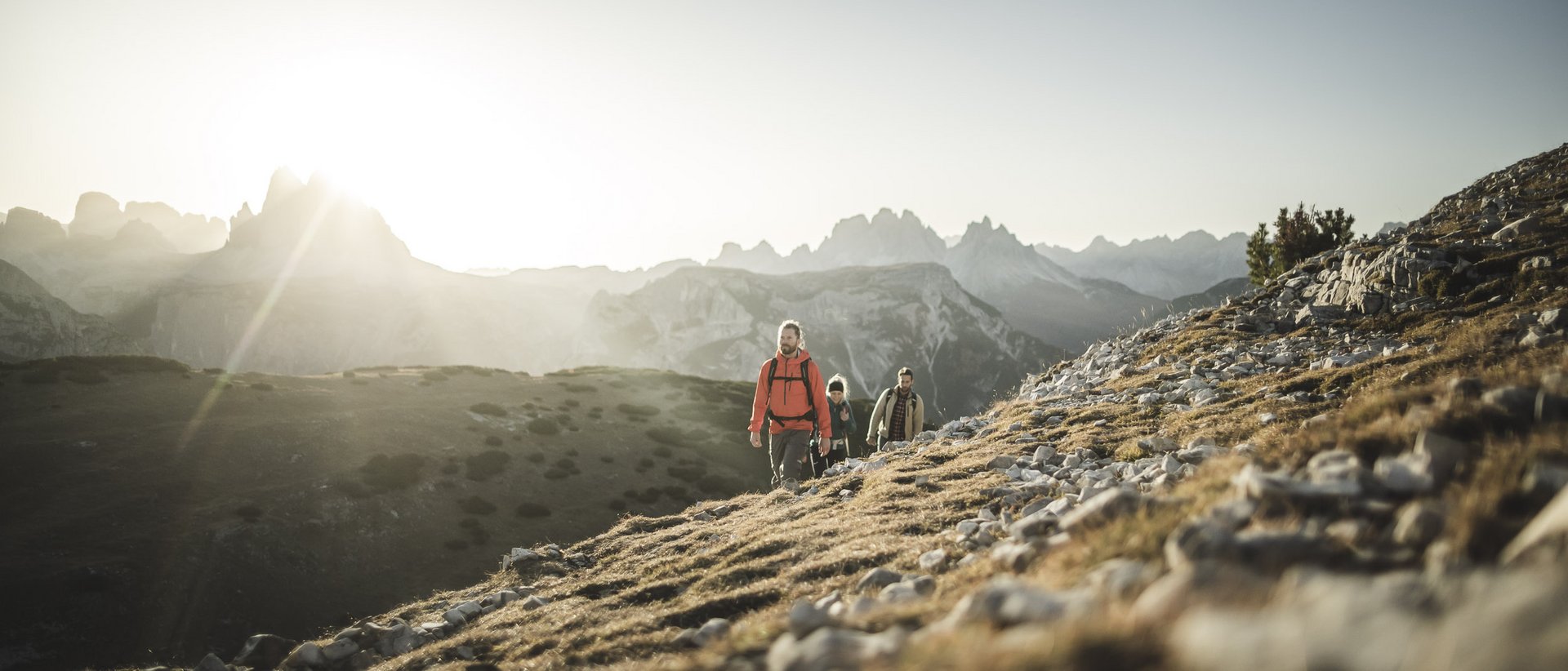 Active holidays in South Tyrol: a great experience Three hikers ascending a mountain at sunrise
