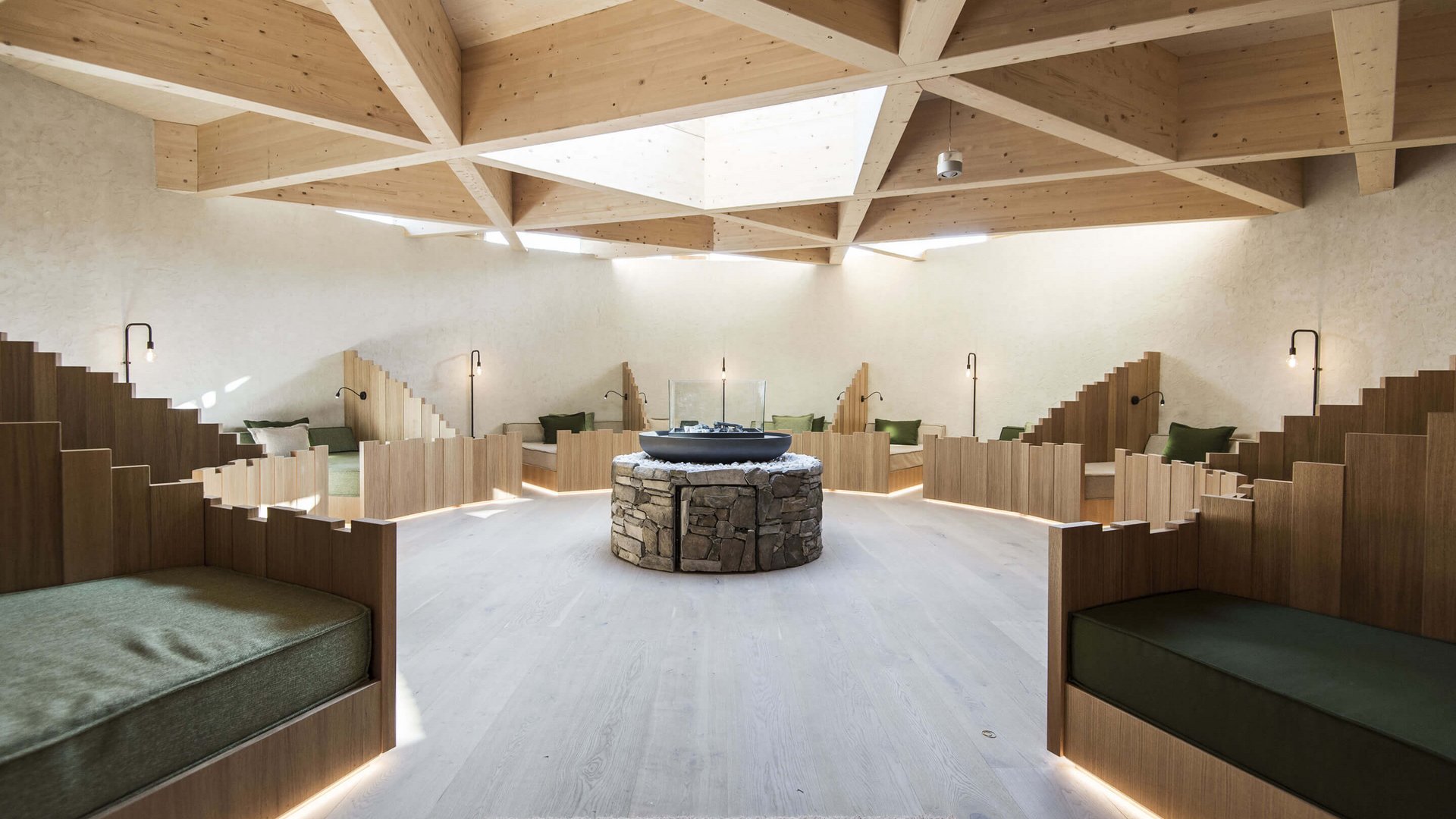 Our sauna, Plan de Corones/Kronplatz in full view Modern relaxation room with wooden ceiling and seating around a central stone fireplace
