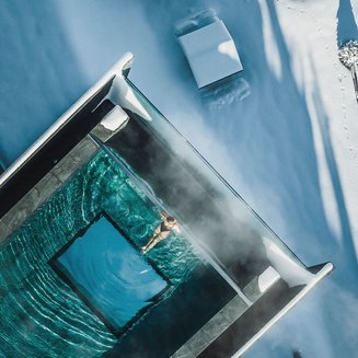 Our hotel vouchers: South Tyrol in gift size Person swimming in heated pool surrounded by snow and winter landscape