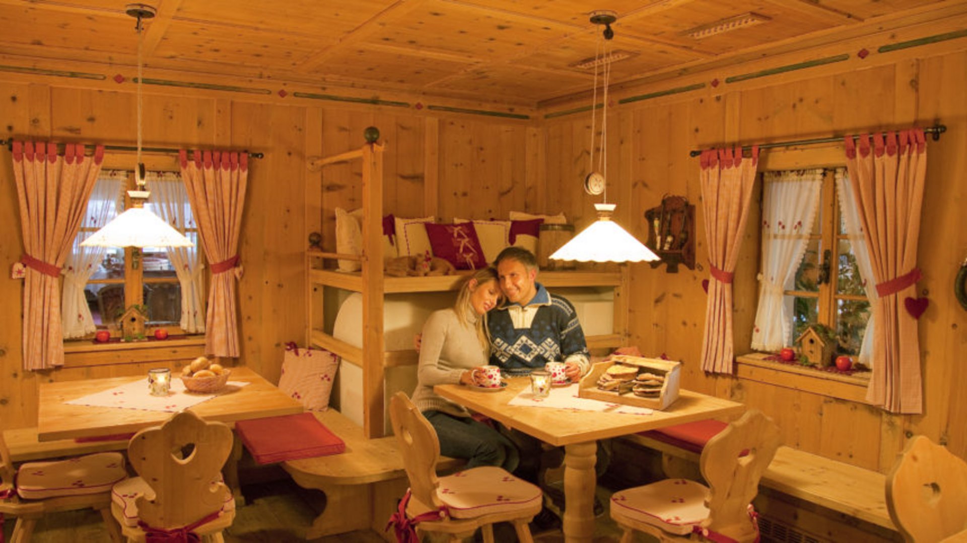 A place to enjoy Couple sitting in a cozy wooden cabin drinking hot beverages