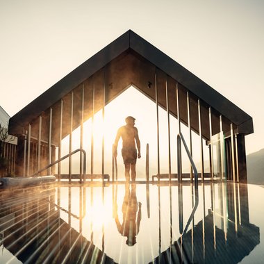 Certified quality for you Person by modern pavilion with reflective water and sunrise