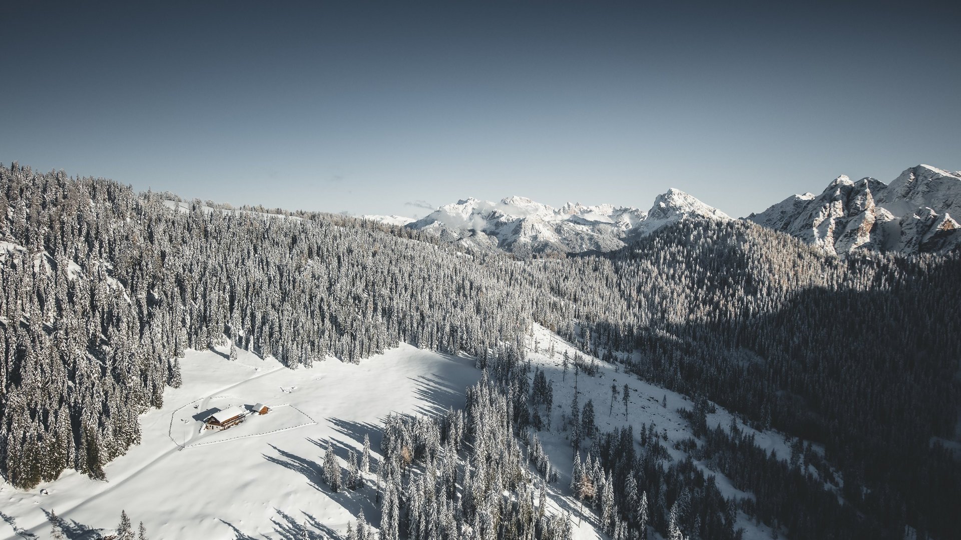 Winter hiking at Plan de Corones/Kronplatz Snow-covered mountain cabin surrounded by snowy pine trees and mountains