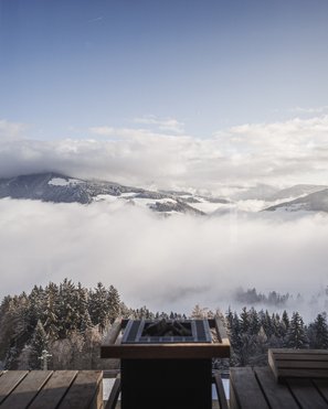 Our wellness hotel in Val Pusteria for relaxation seekers View from a sauna overlooking snowy mountains and misty forest