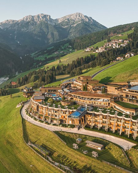 Unser Hotel in Olang zwischen Himmel und Erde Luxushotel auf grüner Bergwiese vor den Alpen bei klarem Himmel