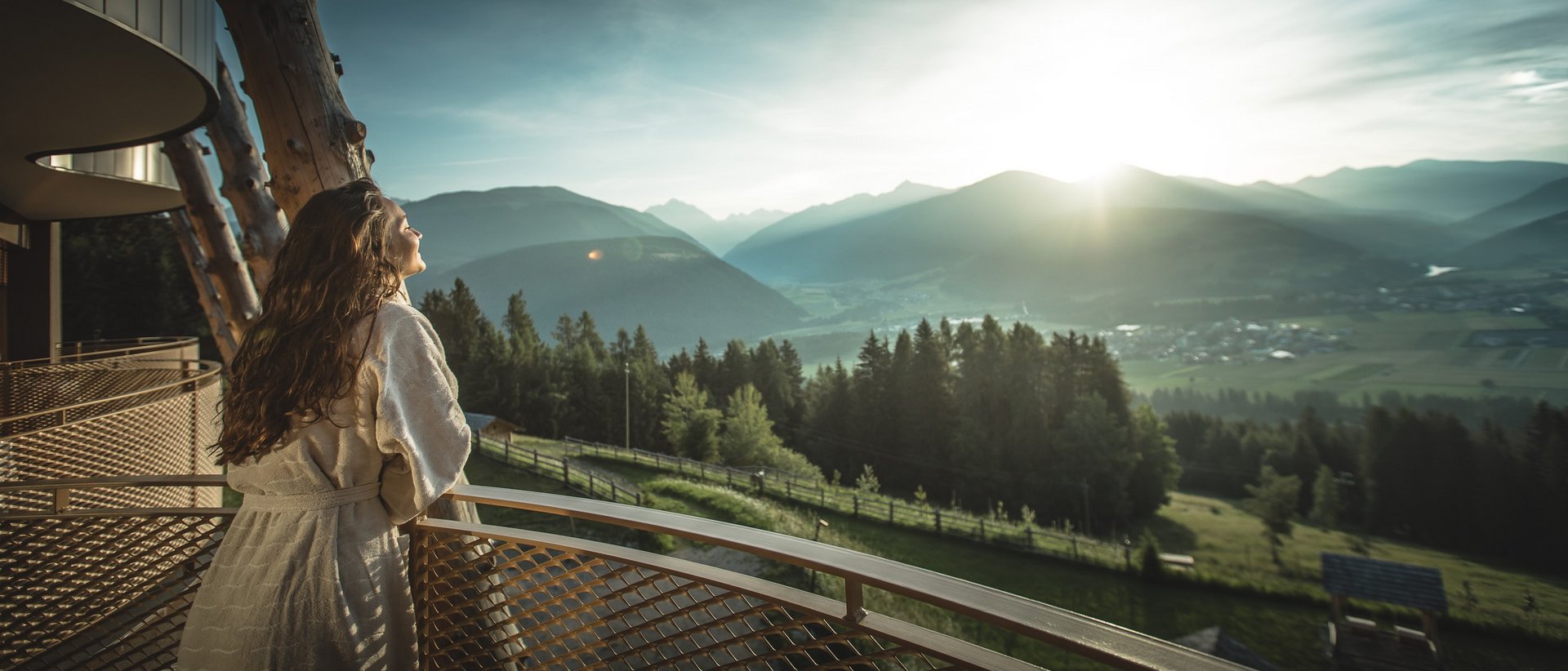 Our 5-star hotel in Italy between heaven and earth Woman in bathrobe enjoying sunrise over mountains from a balcony