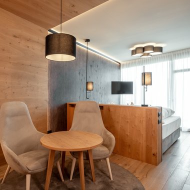 Winter holidays at Plan de Corones/Kronplatz: incredibly diverse Modern hotel room with two chairs, small table and indirect lighting