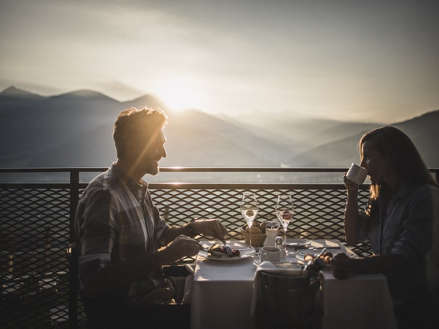 Our 5-star hotel in Italy between heaven and earth Couple enjoying romantic dinner on terrace with mountain view at sunset