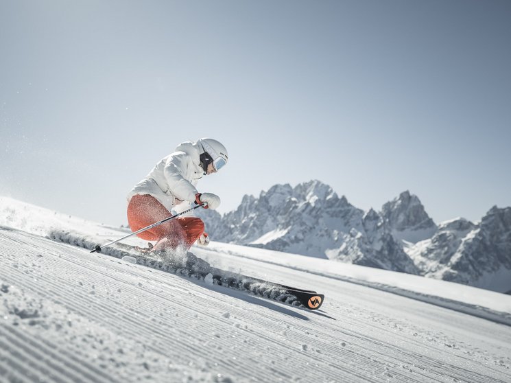 Our hotel vouchers: South Tyrol in gift size Skier skiing on groomed slope with snowy mountains in the background under clear sky