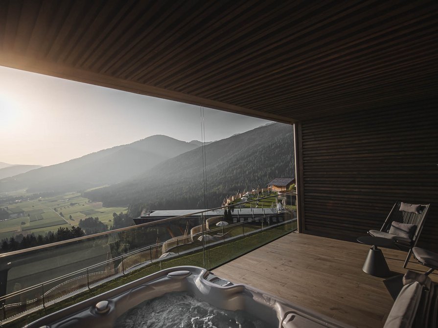 Our 5-star hotel in Italy between heaven and earth Balcony with hot tub and chairs overlooking mountains at sunset