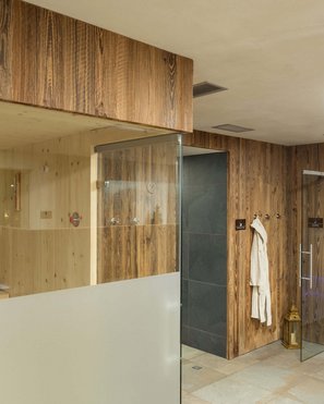 Our wellness hotel in Val Pusteria for relaxation seekers Modern sauna area with wooden panels and steam room with blue lighting