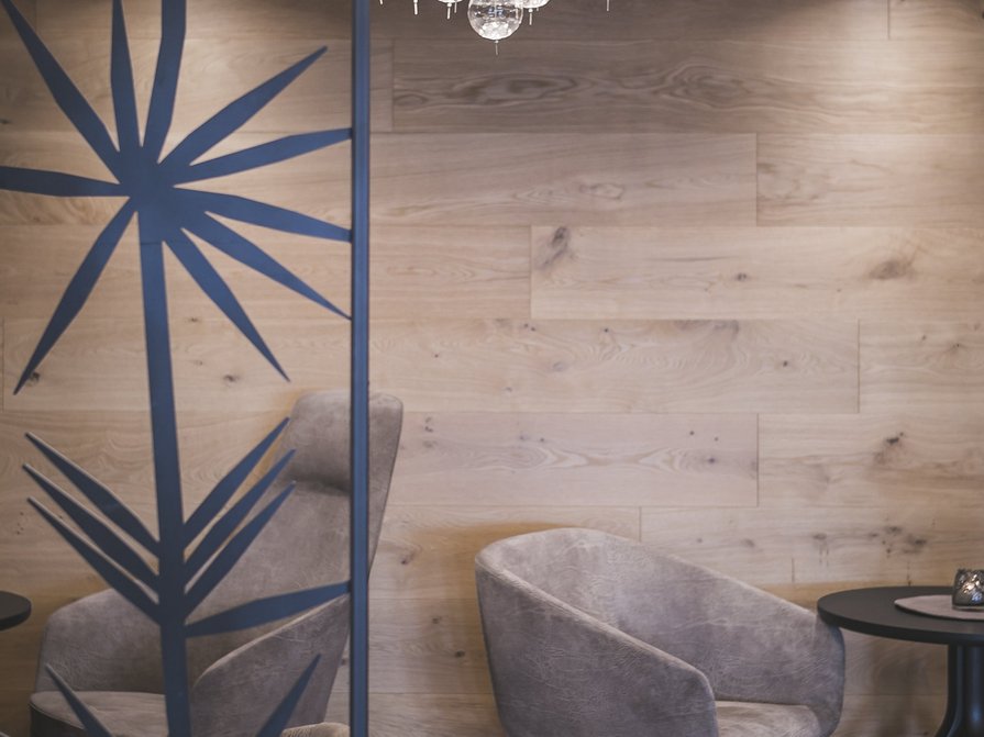 Our 5-star hotel in Italy between heaven and earth Cozy seating area with gray armchair and round table in front of wooden wall