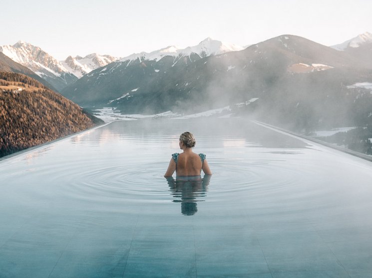 Our wellness hotel in Val Pusteria for relaxation seekers Woman in heated infinity pool with mountain view