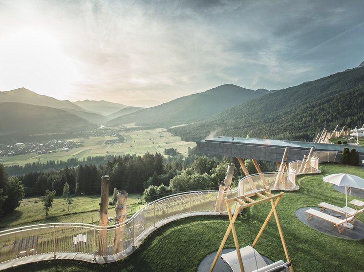 Alpenreych & Hubertus Park Sunny terrace with loungers, swings, and mountain valley view