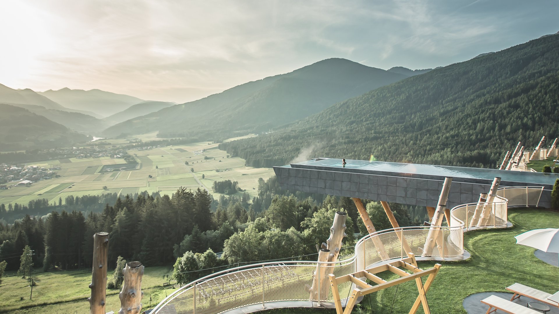 Il nostro hotel con infinity pool in Alto Adige: una meraviglia Terrazza soleggiata con sedie a sdraio, altalene e vista sulle montagne