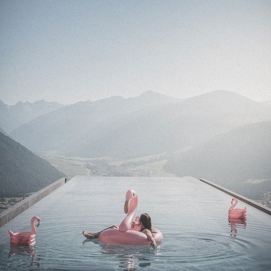 Our sauna, Plan de Corones/Kronplatz in full view Relaxed person on flamingo float in infinity pool with mountain view