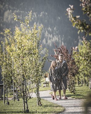 Alpenreych & Hubertus Park Couple in robes walking on a tree-lined path outdoors