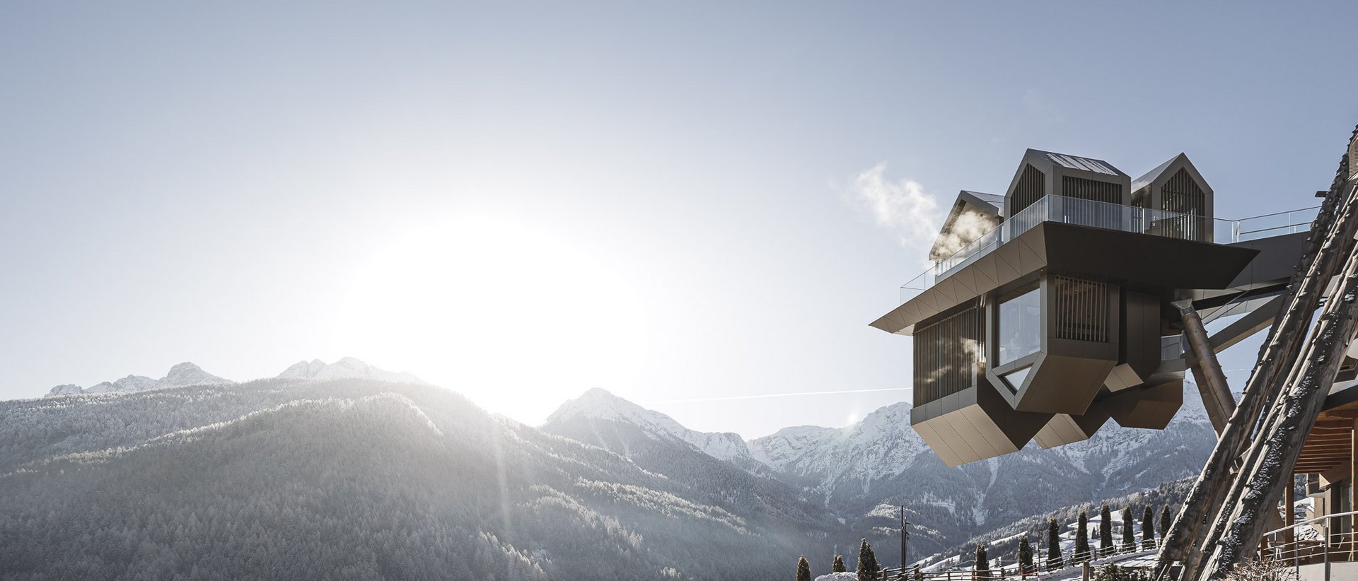 Our wellness hotel in Val Pusteria for relaxation seekers Modern balcony overlooking snow-covered mountains with sunlight