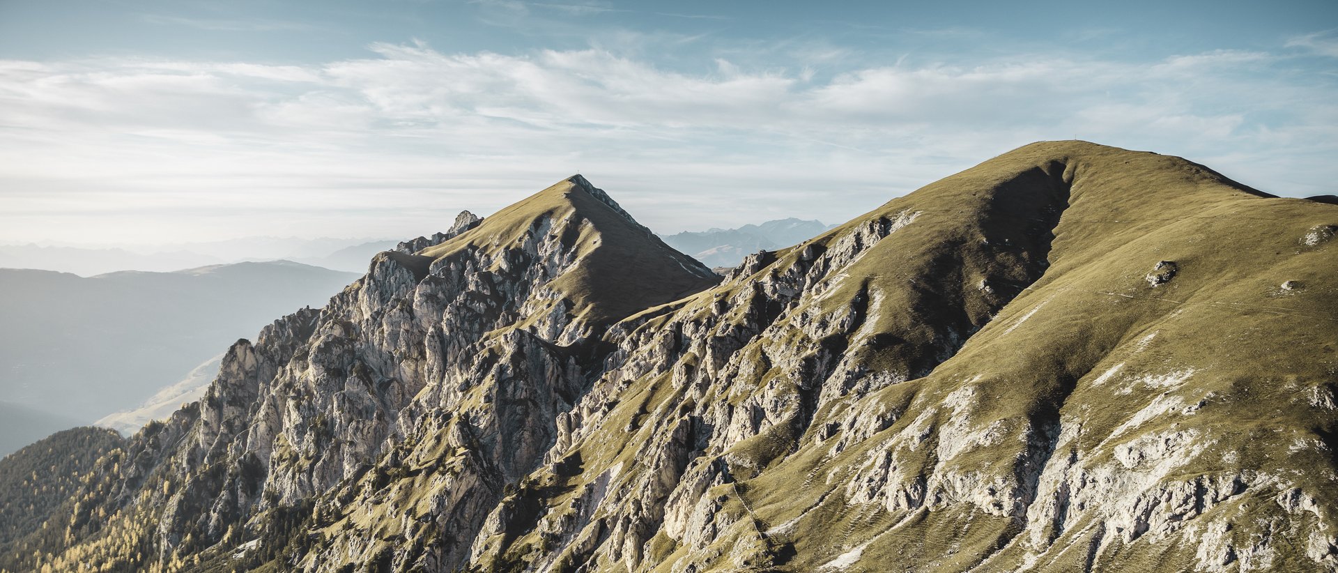 Active holidays in South Tyrol: a great experience Mountain ridge with steep rocks and forested valleys under a clear sky