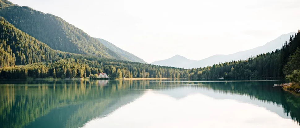 Our 5-star hotel in Italy between heaven and earth Mountain lake with reflected trees and a house on the shore