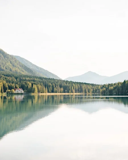 Our 5-star hotel in Italy between heaven and earth Mountain lake with reflected trees and a house on the shore